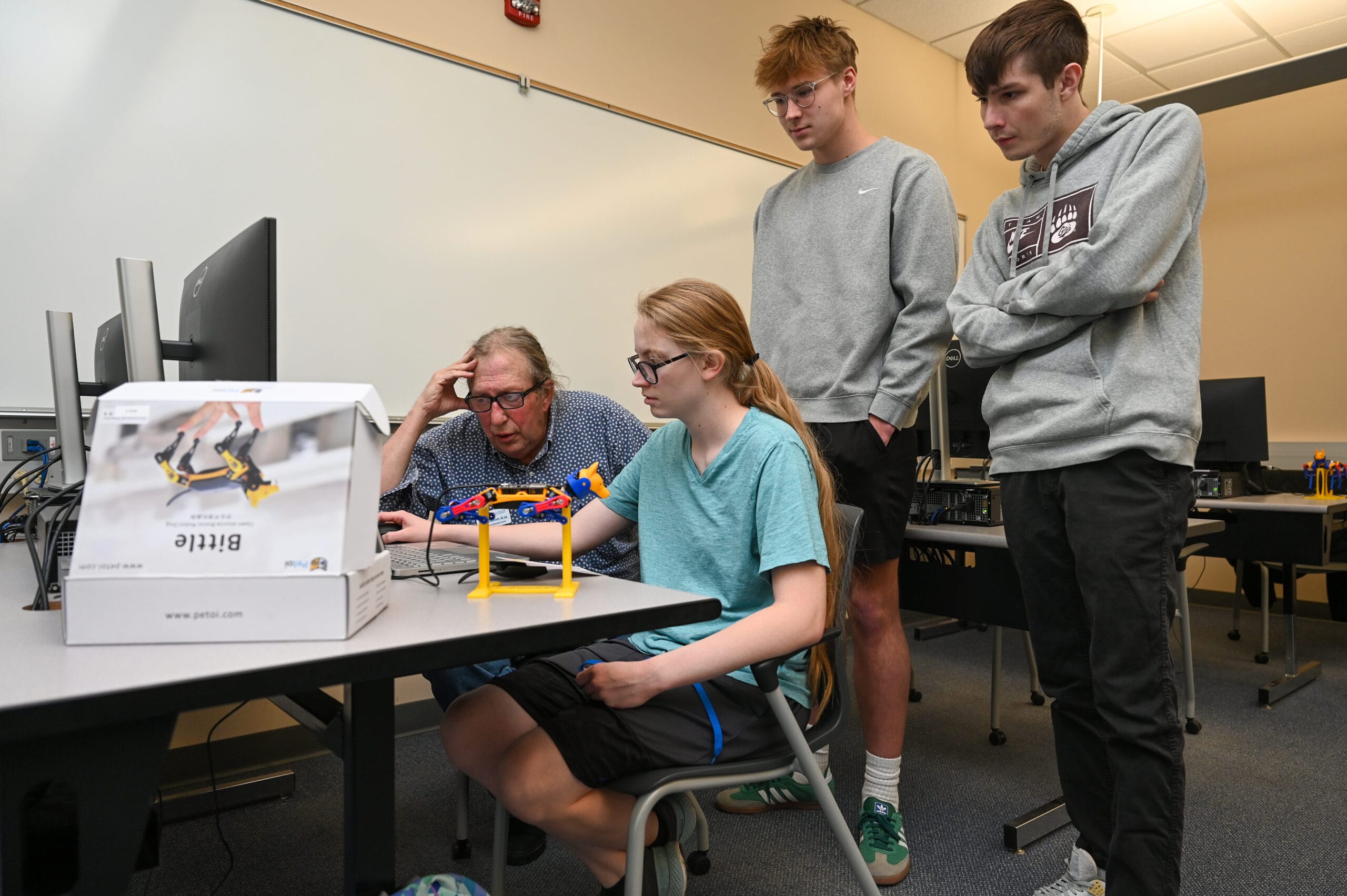 Students working with a robotic dog during computer programming class.