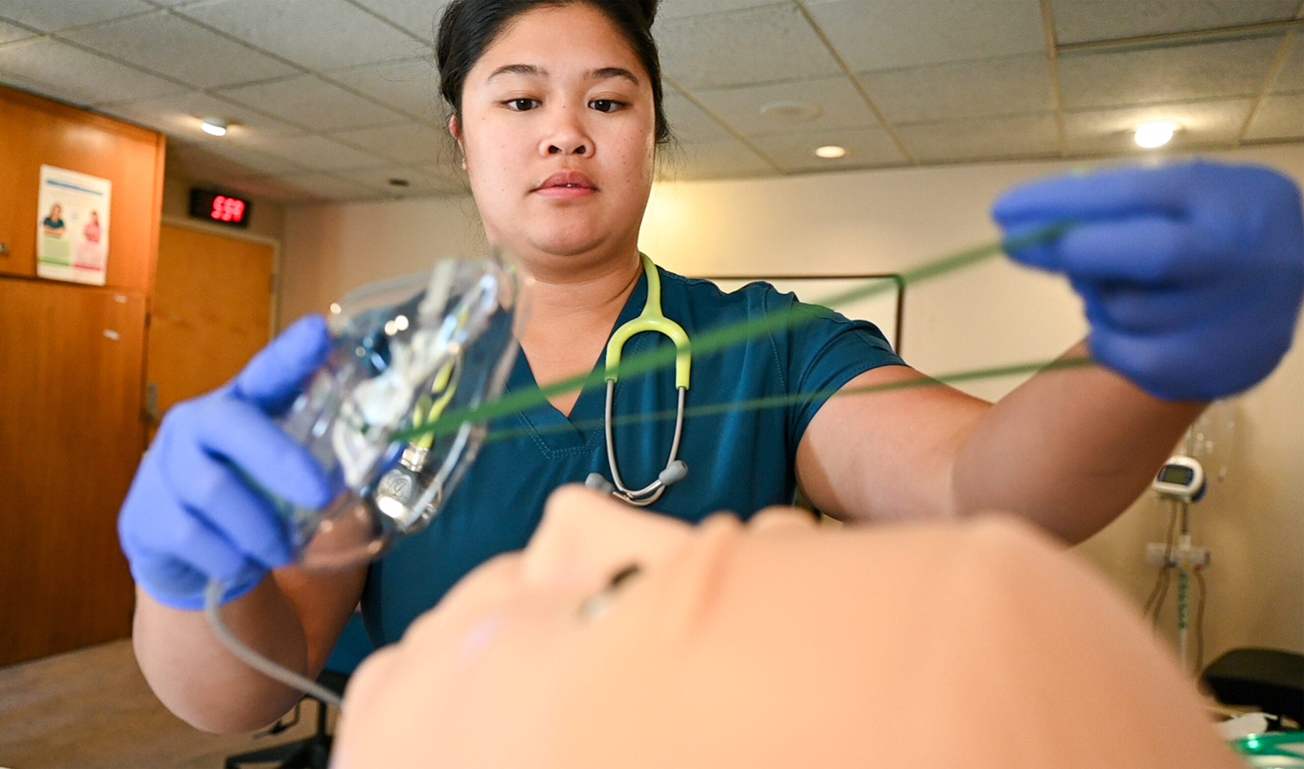 Student placing mask on training mannequin